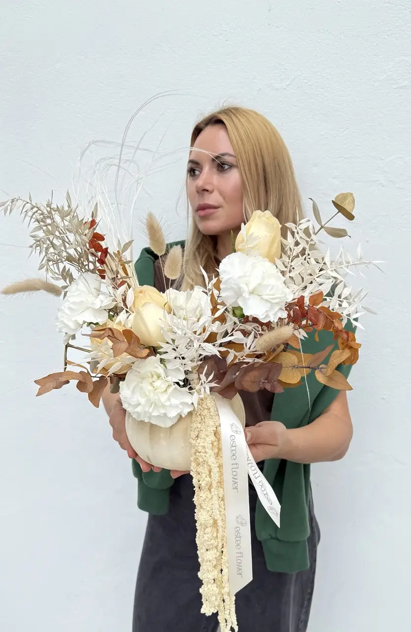 Seasonal flower arrangement in a white pumpkin with gold accents