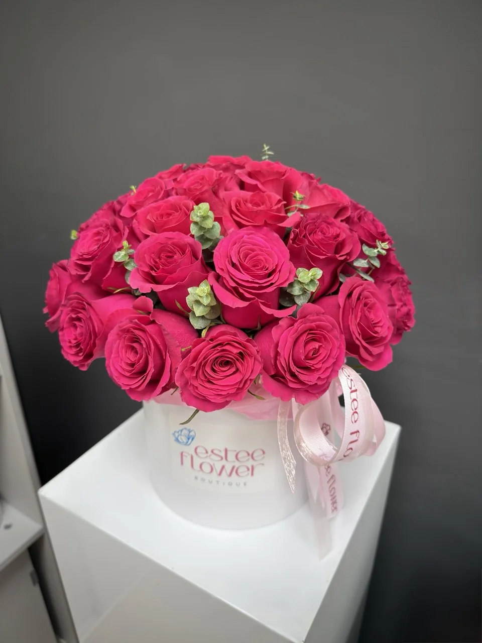 hot pink roses in a hat box with eucalyptus arrangement